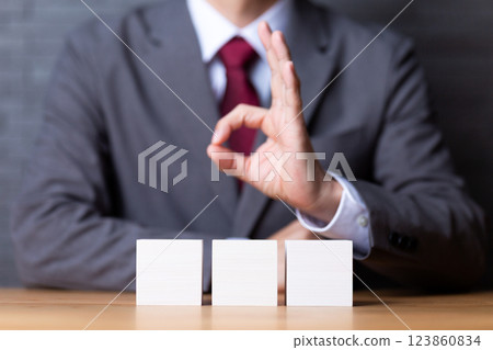 三塊白色木塊和一位豎起大拇指的中年男性商人 123860834