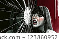 Southeast asian woman crying behind broken glass reflecting her despair 123860952
