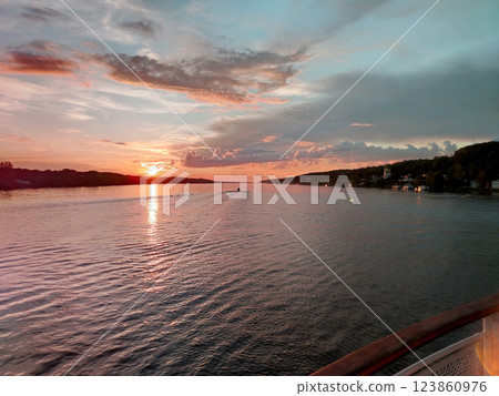 Golden sunset over the river, view from the motorboat on the calm water surface and houses on the shore, beautiful evening panorama Golden sunset over the river, view from the motorboat on the calm water surface and houses on the shore, beautiful evening panorama 123860976