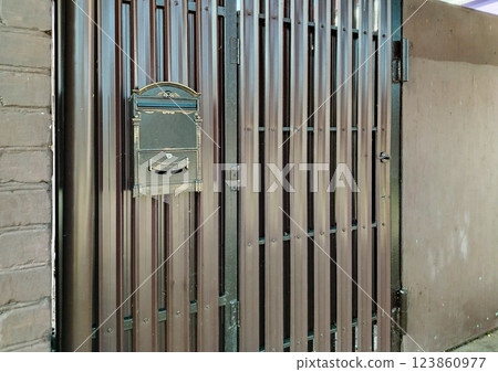 Modern mailbox on a new metal gate made of siding and profiles Modern mailbox on a new metal gate made of siding and profiles 123860977
