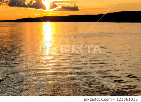Golden sunset over the river, view from the motorboat on the calm water surface and houses on the shore, beautiful evening panorama Golden sunset over the river, view from the motorboat on the calm water surface and houses on the shore, beautiful evening panorama 123861018