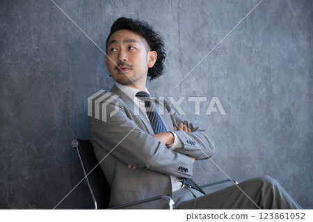 A businessman in a suit sitting in a chair and looking up, turning around. Image of success and goals A businessman in a suit sitting in a chair and looking up, turning around. Image of success and goals 123861052