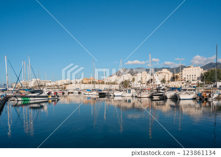 Scenic marina with sailboats and urban skyline under clear blue sky 123861134