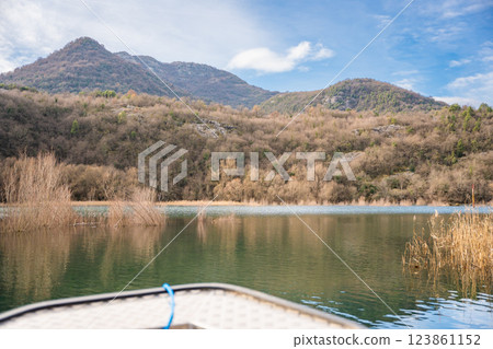 View from the boat of trees and reeds on River Crnojevica, place near Lake Skadar in Montenegro surrounded by mountain peaks in winter time View from the boat of trees and reeds on River Crnojevica, place near Lake Skadar in Montenegro surrounded by mountain peaks in winter time 123861152