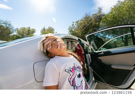 Young caucasian girl relaxing by car under sunlight in nature Young caucasian girl relaxing by car under sunlight in nature 123861156