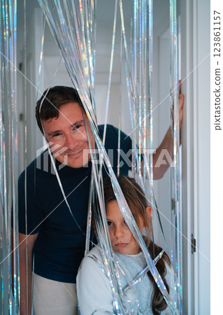 Caucasian male adult and young female in cheerful pose with shimmering streamers Caucasian male adult and young female in cheerful pose with shimmering streamers 123861157