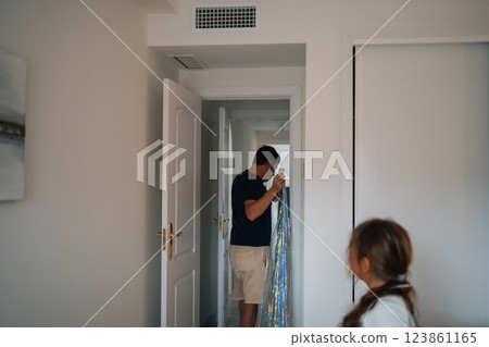 Hispanic adult male unwrapping decorated doorway as hispanic child observes in home Hispanic adult male unwrapping decorated doorway as hispanic child observes in home 123861165