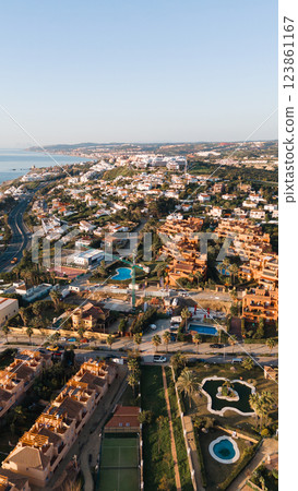 Coastal mediterranean town with villas and pools in scenic landscape Coastal mediterranean town with villas and pools in scenic landscape 123861167