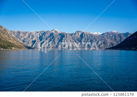 Bay of Kotor in Montenegro and the top of high snow-capped mountains, small settlements on the coast and the bright blue waters of the Adriatic Sea. 123861170