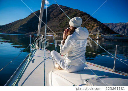 Woman hands holding thermo mug sitting on bow of the yacht during sailing in the morning in winter time in Adriatic sea, relaxation in yachting time 123861181