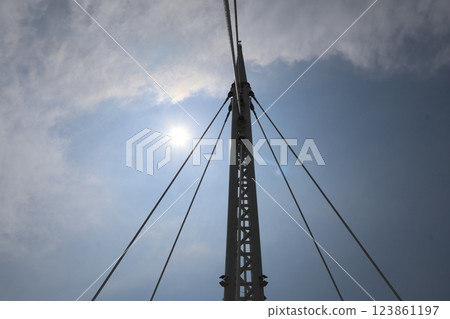 A landscape with a shining white sun, white clouds, blue sky and a steel tower A landscape with a shining white sun, white clouds, blue sky and a steel tower 123861197