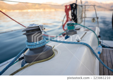 Close-up of a yacht winch with blue ropes secured, set against the scenic backdrop of the Bay of Kotor. Concept of sailing, nautical adventure, and maritime lifestyle 123861210