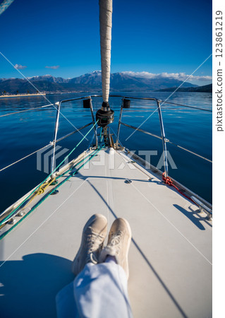 Feet of young woman on bow of the yacht during sailing in the morning in winter time in Adriatic sea, yacht life and yachting concept 123861219