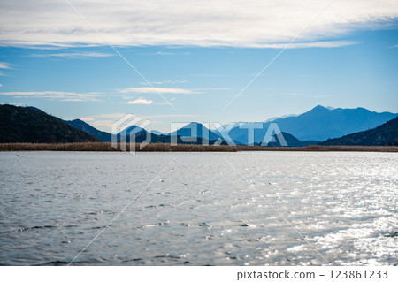 Trees and reeds on River Crnojevica, place near Lake Skadar in Montenegro surrounded by mountain peaks in winter time Trees and reeds on River Crnojevica, place near Lake Skadar in Montenegro surrounded by mountain peaks in winter time 123861233