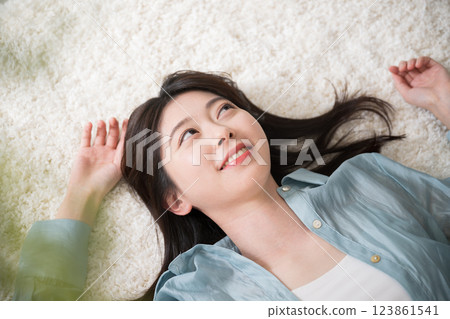 Aerial view of a young woman lying on her back in a room with a smile, looking at the camera, relaxing or taking a nap, wide angle Aerial view of a young woman lying on her back in a room with a smile, looking at the camera, relaxing or taking a nap, wide angle 123861541