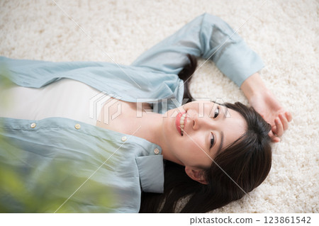 Aerial view of a young woman lying on her back in a room with a smile, looking at the camera, relaxing or taking a nap, wide angle 123861542