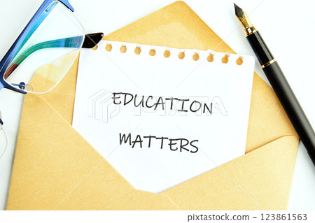 A note reading education matters is placed inside an envelope on a desk alongside glasses and a pen. This reflects the importance of education in business finance contexts A note reading education matters is placed inside an envelope on a desk alongside glasses and a pen. This reflects the importance of education in business finance contexts 123861563