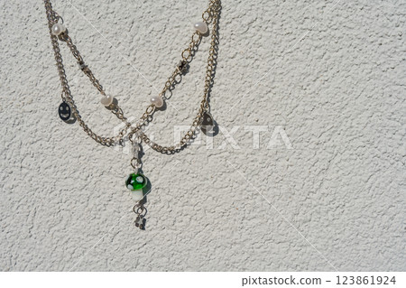 Trendy layered necklace with mushroom pendant and pearls against textured white wall Trendy layered necklace with mushroom pendant and pearls against textured white wall 123861924