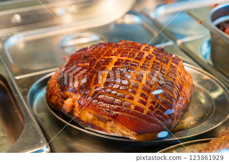 Glazed roasted ham with crispy scored skin in a stainless steel tray 123861929