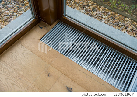 Floor heating vent near a large window in a modern home Floor heating vent near a large window in a modern home 123861967