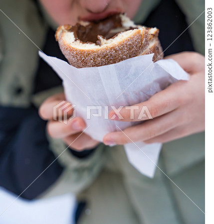 Child eating traditional Czech trdelnik with chocolate filling in winter 123862003