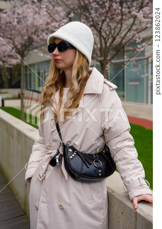 Stylish woman in spring outfit wearing sunglasses and a bucket hat in the city 123862024