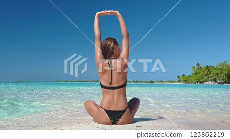 Young woman is enjoying her vacation in the maldives by practicing yoga and meditation on a pristine white sand beach Young woman is enjoying her vacation in the maldives by practicing yoga and meditation on a pristine white sand beach 123862219