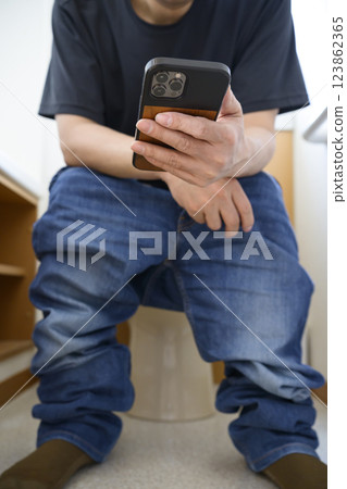男人在廁所看智慧型手機 123862365