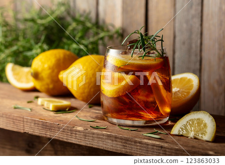Hard seltzer or alcoholic cocktail with ice, rosemary and lemon slices on a old wooden table. 123863033