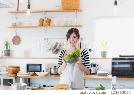 一個圍裙,在廚房裡做飯的女人 一個圍裙,在廚房裡做飯的女人 123863053