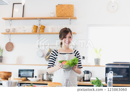 一個圍裙,在廚房裡做飯的女人 一個圍裙,在廚房裡做飯的女人 123863060