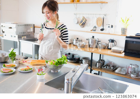 A woman in an apron cooking in the kitchen A woman in an apron cooking in the kitchen 123863074