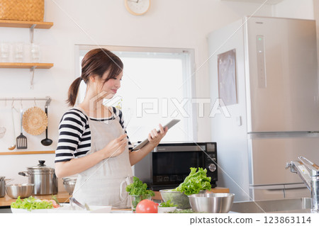 A woman in an apron cooking in the kitchen 123863114