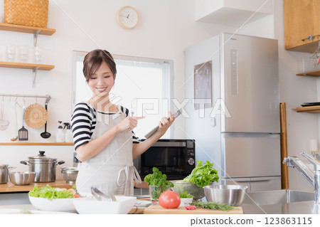 A woman in an apron cooking in the kitchen 123863115