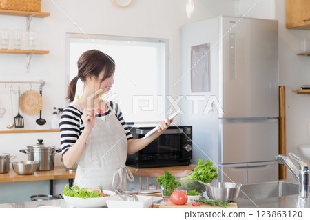 一個圍裙,在廚房裡做飯的女人 一個圍裙,在廚房裡做飯的女人 123863120