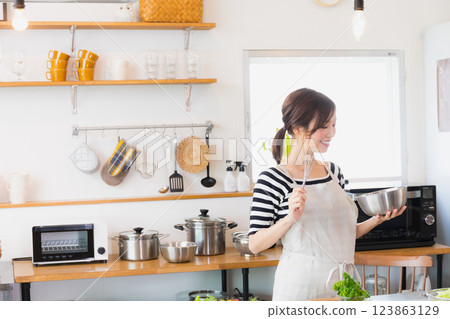 A woman in an apron cooking in the kitchen 123863129