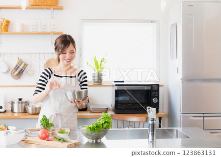 A woman in an apron cooking in the kitchen 123863131