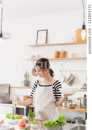 A woman in an apron cooking in the kitchen 123863141