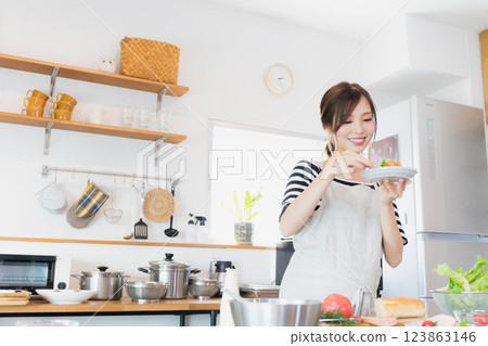A woman in an apron cooking in the kitchen 123863146