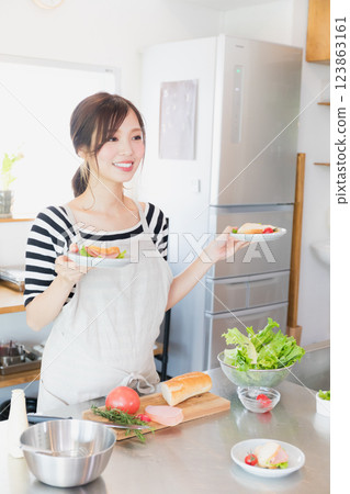 一個圍裙,在廚房裡做飯的女人 一個圍裙,在廚房裡做飯的女人 123863161
