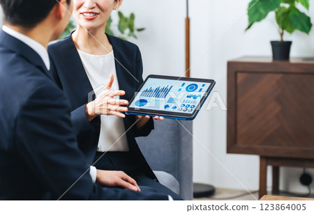 一群男女商務人士在大廳一邊看平板電腦一邊討論業務 一群男女商務人士在大廳一邊看平板電腦一邊討論業務 123864005