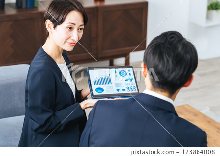一群男女商務人士在大廳一邊看平板電腦一邊討論業務 一群男女商務人士在大廳一邊看平板電腦一邊討論業務 123864008
