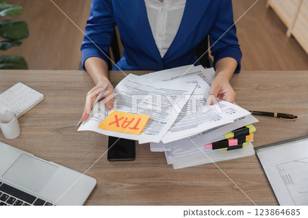 Tax documentation and business management. Professional woman organizing financial papers with a focus on taxes. Tax documentation and business management. Professional woman organizing financial papers with a focus on taxes. 123864685