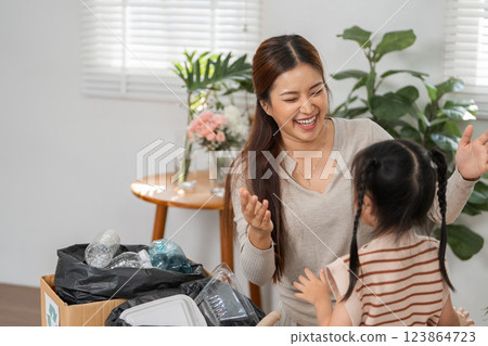 Joy of Recycling and Family Interaction. A mother smiles warmly while sharing a recycling moment with her daughter. 123864723