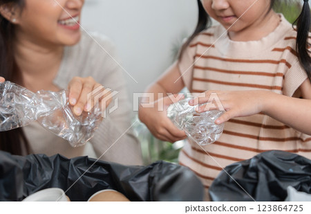 Eco-Friendly Practices and Family Connection. A mother and daughter bond while sorting recyclables. 123864725