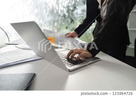 Business analysis. Professional accountant working on a laptop while reviewing financial documents in the office. 123864726