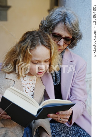 Grandmother and granddaughter reading a book in the library yard 123864805