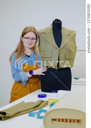 female fashion designer or seamstress tries on a jacket on a mannequin. design patterns 123865080