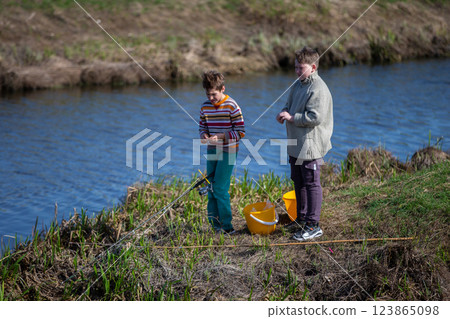 The boys are fishing on a small river. Friends go fishing in the summer. The boys are fishing on a small river. Friends go fishing in the summer. 123865098