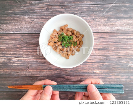 Woman's hands holding natto and chopsticks on a wooden table Woman's hands holding natto and chopsticks on a wooden table 123865151